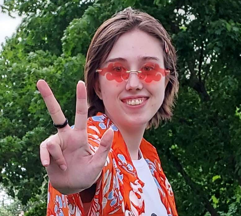Photo of Jordan Wildman, smiling and giving a piece sign to the camera.